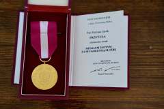 Złoty Medal za długoletnią służbę wraz z oficjalnym dokumentem nadania podpisanym przez Prezydenta Rzeczypospolitej Polskiej.